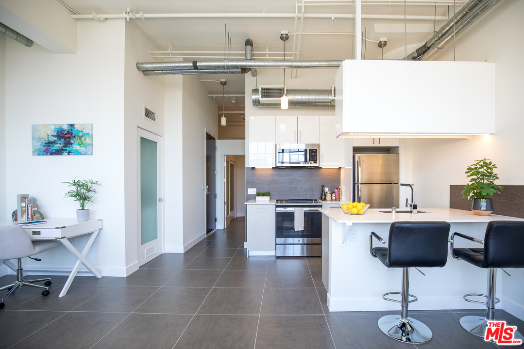 a kitchen with stainless steel appliances kitchen island hardwood floor and chairs