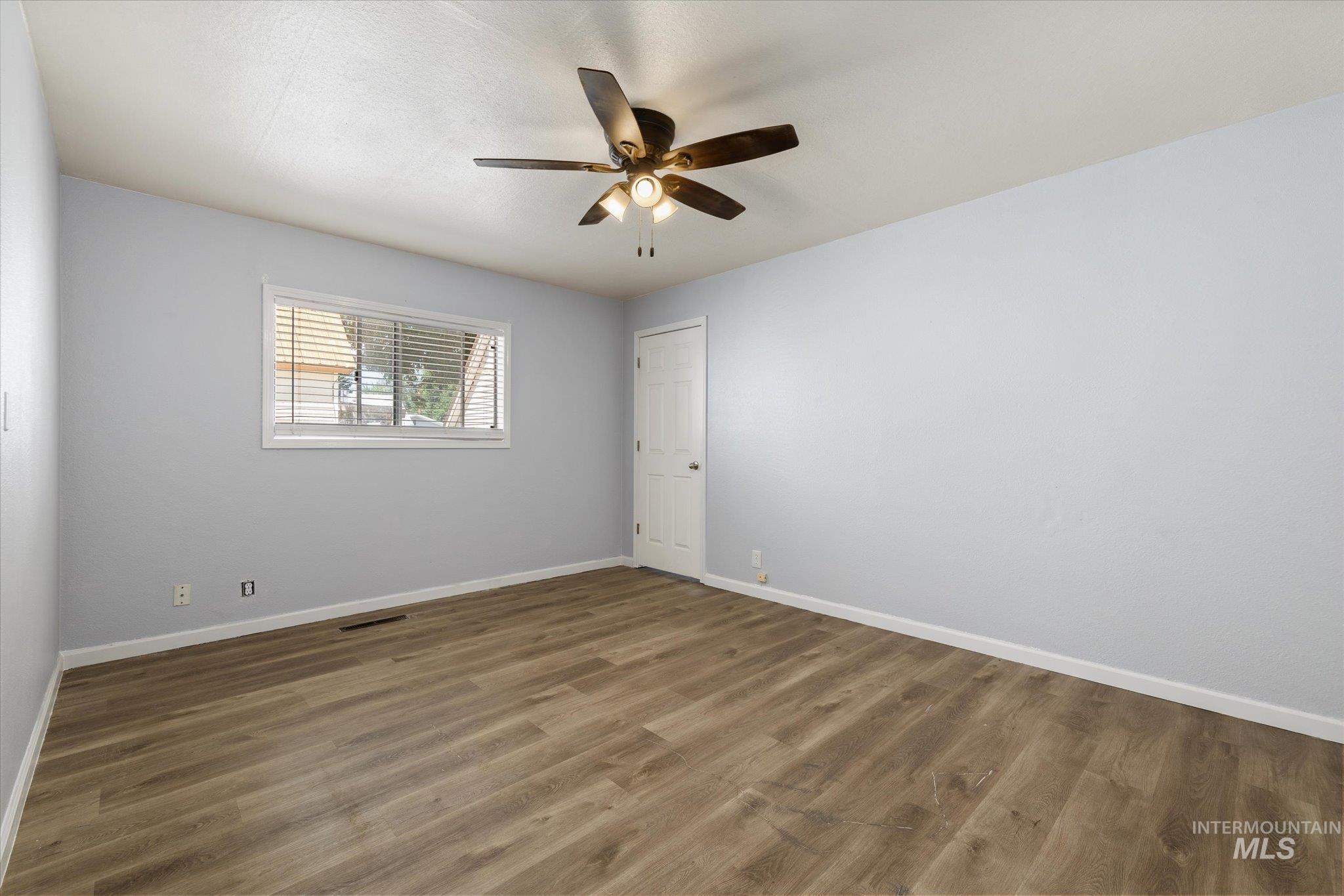 918 West 3rd Street Weiser, ID 83672 - Photo 24 of 36 Spacious room featuring wood-finish flooring, light gray walls, white trim, and a ceiling fan with integrated lighting