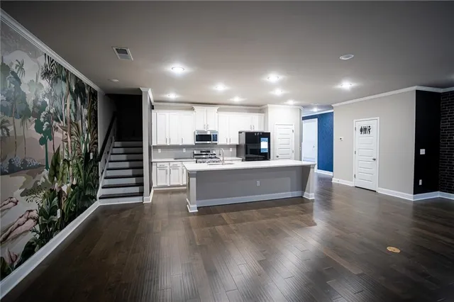 a large kitchen with stainless steel appliances a large counter top a stove and a wooden floors