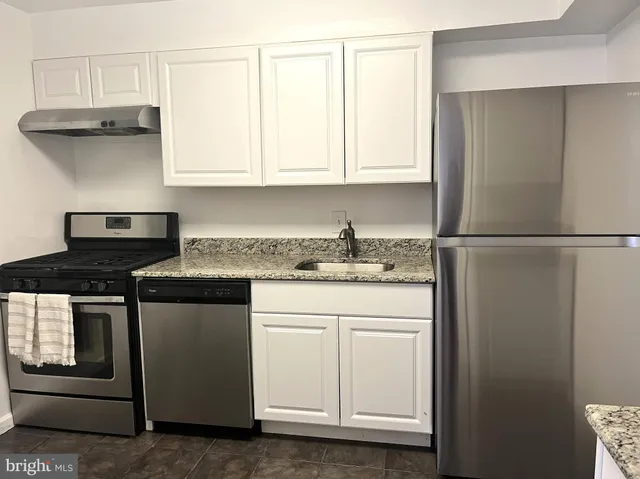 a kitchen with granite countertop white cabinets and a stove