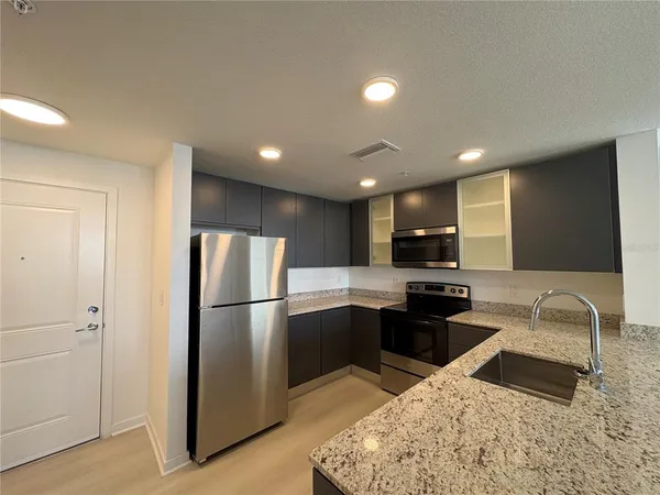 a kitchen with stainless steel appliances granite countertop a refrigerator sink and stove