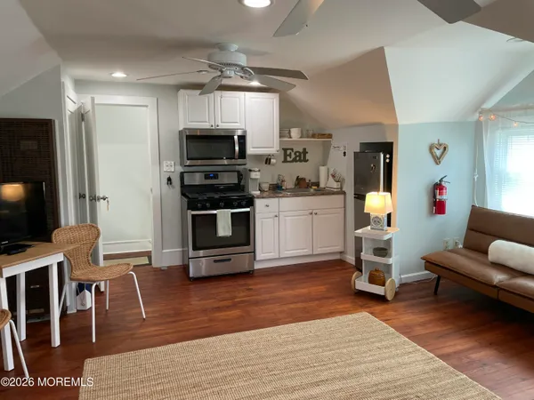 a living room with stainless steel appliances furniture wooden floor and a view of kitchen
