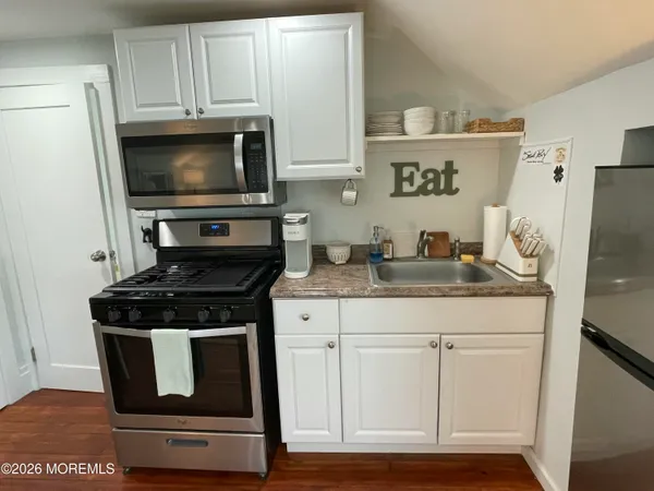 a kitchen with white cabinets and black appliances