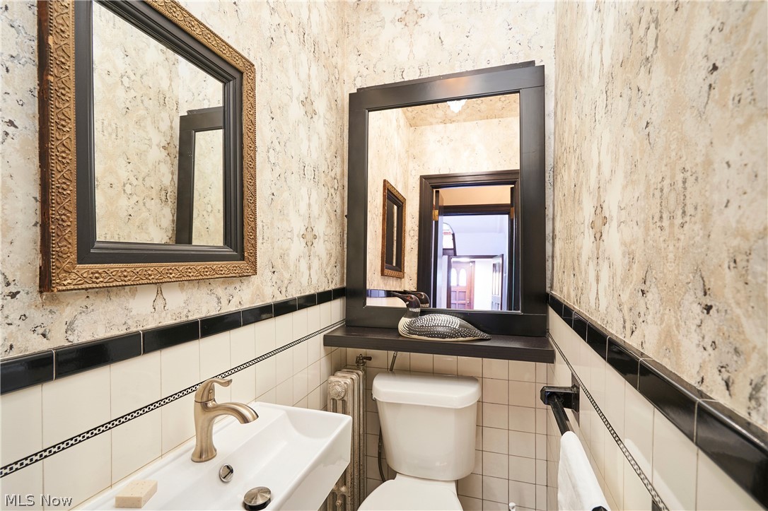 644 Ridgecrest Road Akron, OH 44303 - Photo 22 of 47 Compact powder room featuring a wall-mounted sink with a brushed nickel faucet, a white toilet, and a dark wood-framed mirror