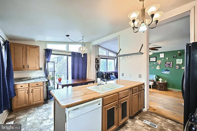 a hall with kitchen island a stove a counter space a sink and cabinets