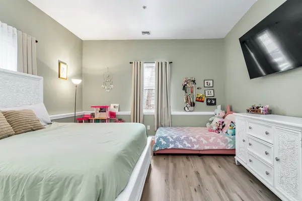 a bedroom with a bed and a flat tv screen on dresser