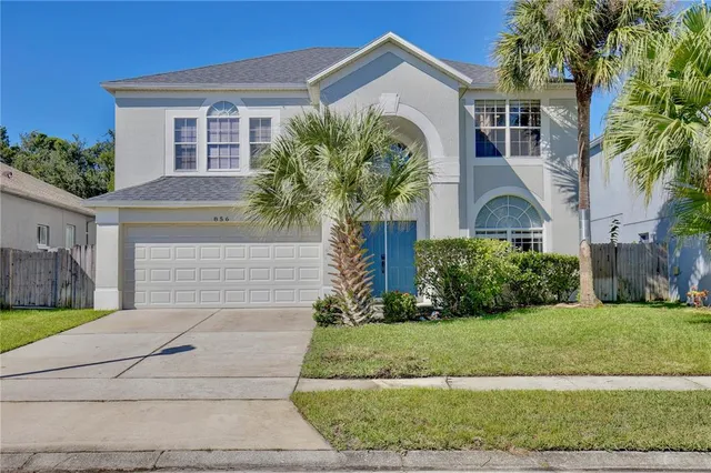 a front view of a house with a yard and potted plants
