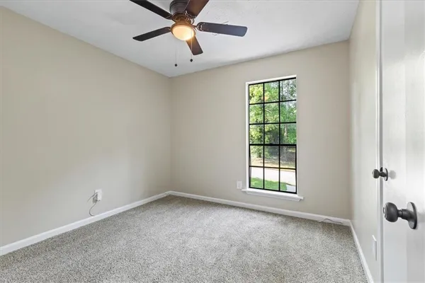 an empty room with a window and a fan