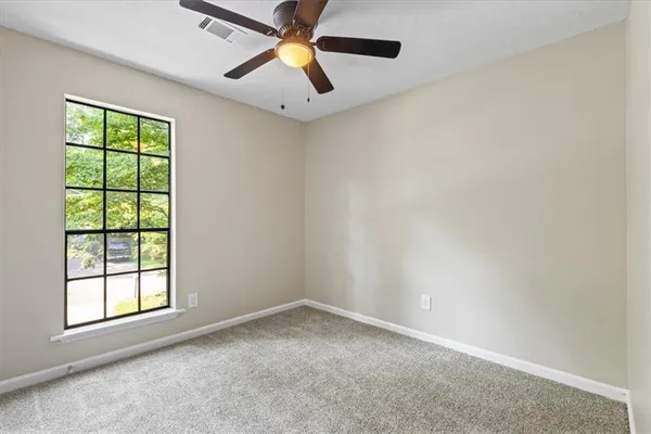 an empty room with windows and fan