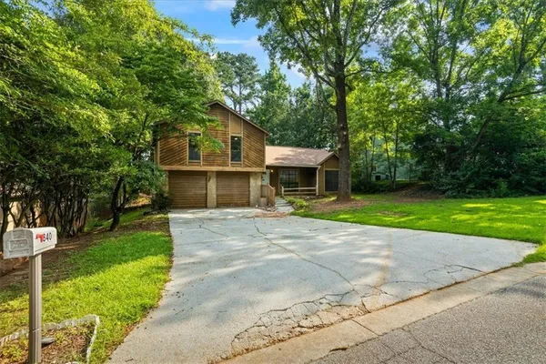 a front view of a house with a garden and trees
