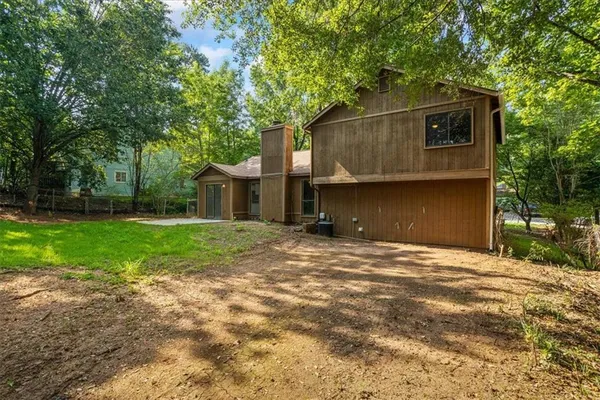 a backyard of a house with plants and large tree