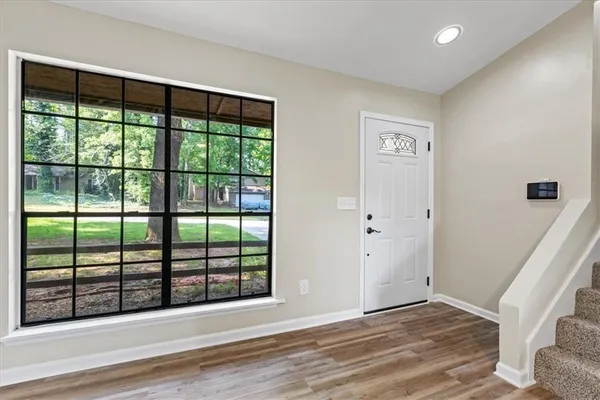 a view of an empty room with wooden floor and a window