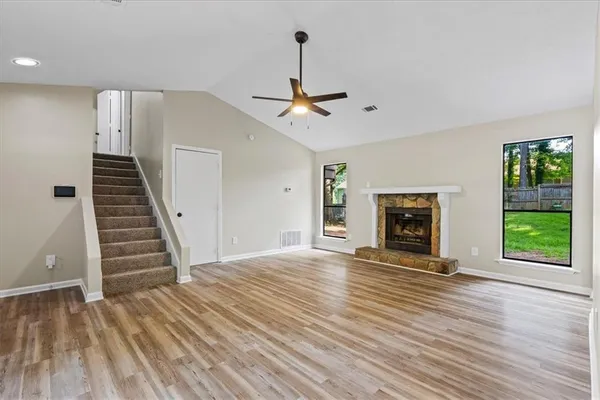 a view of an empty room with wooden floor fireplace and a window