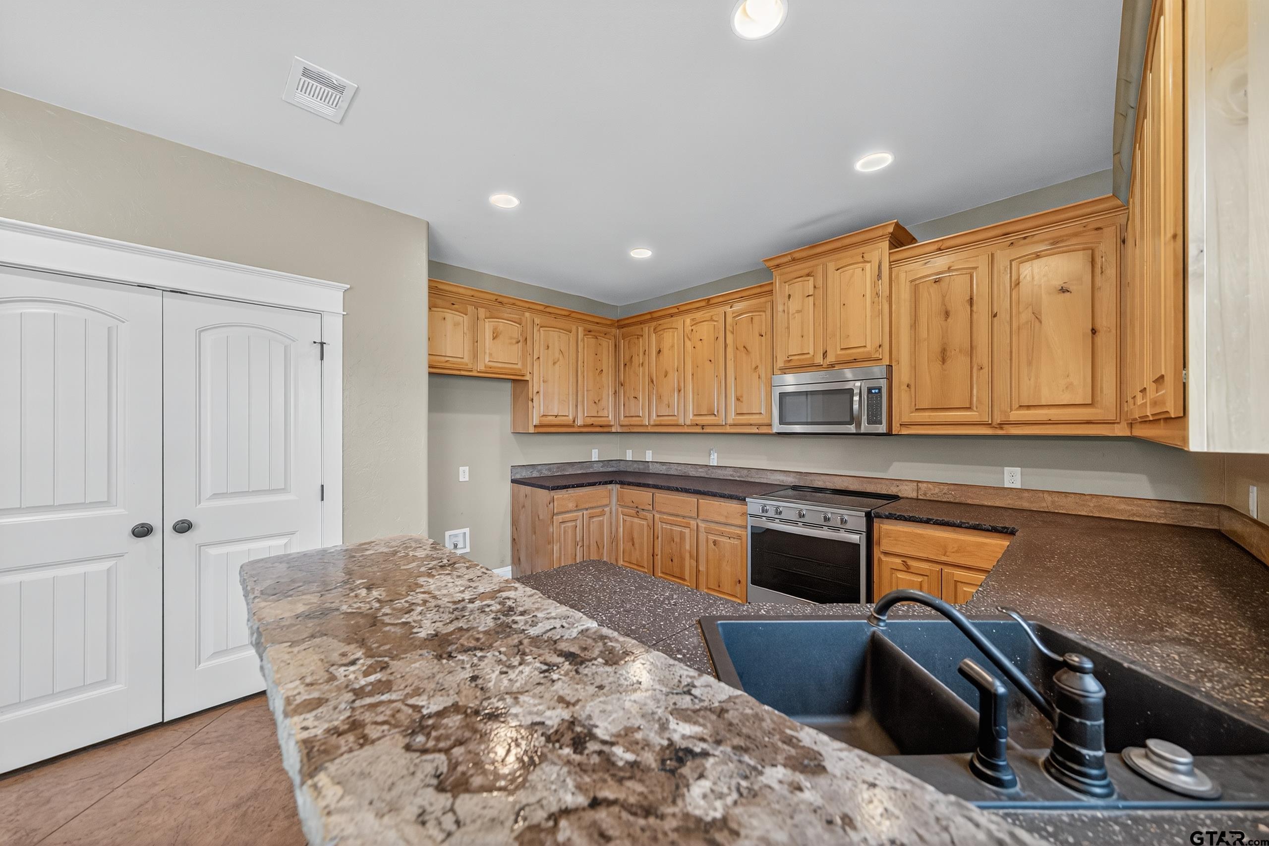 709 Linus Lane Lindale, TX 75771 - Photo 15 of 40 a kitchen with stainless steel appliances granite countertop a stove a sink and a microwave