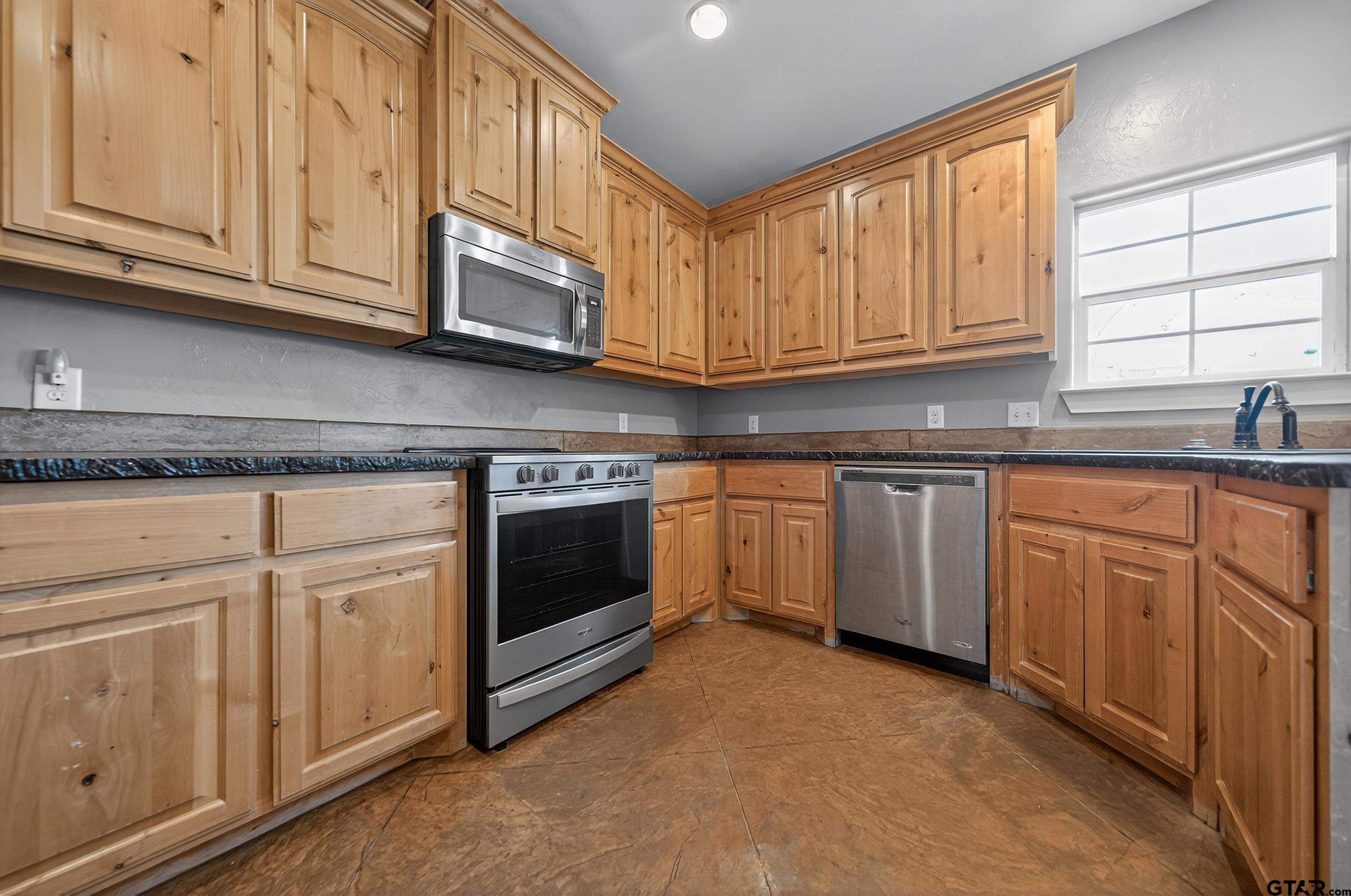 709 Linus Lane Lindale, TX 75771 - Photo 18 of 40 a kitchen with granite countertop white cabinets stainless steel appliances and sink