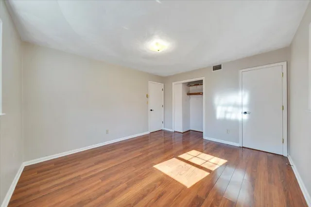 an empty room with wooden floor and windows