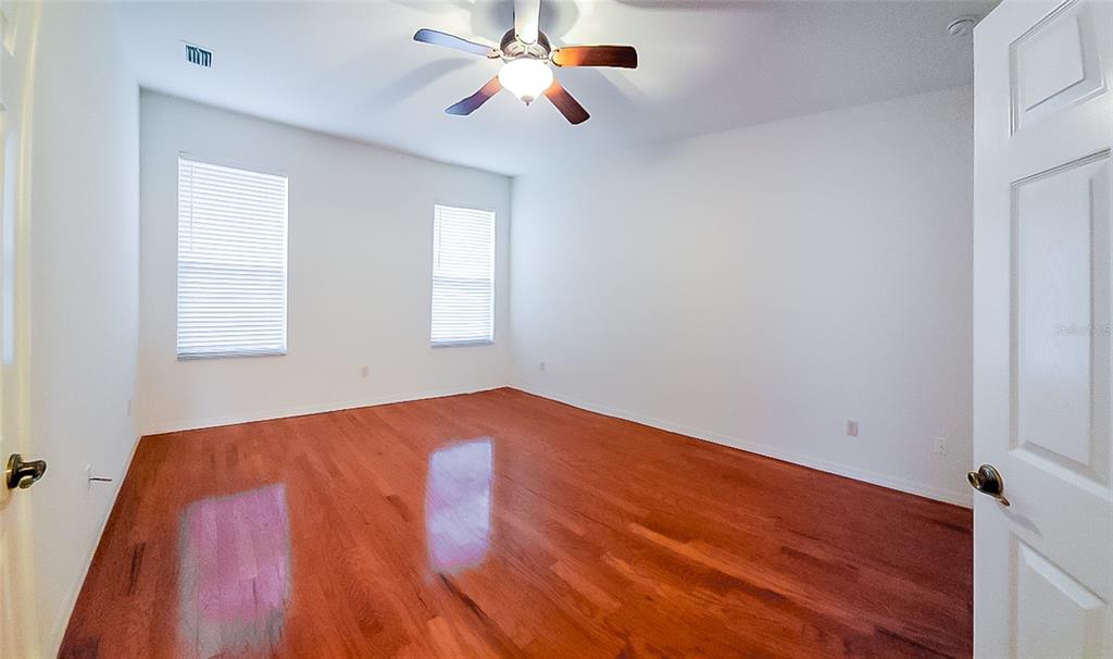 16299 Southwest 14th Avenue Road Ocala, FL 34473 - Photo 18 of 50 an empty room with wooden floor ceiling fan and windows