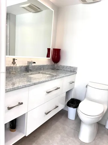 a bathroom with a granite countertop toilet sink and mirror