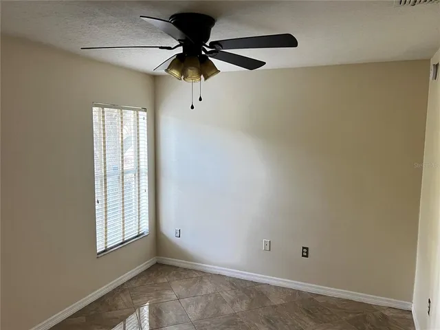 an empty room with windows and fan