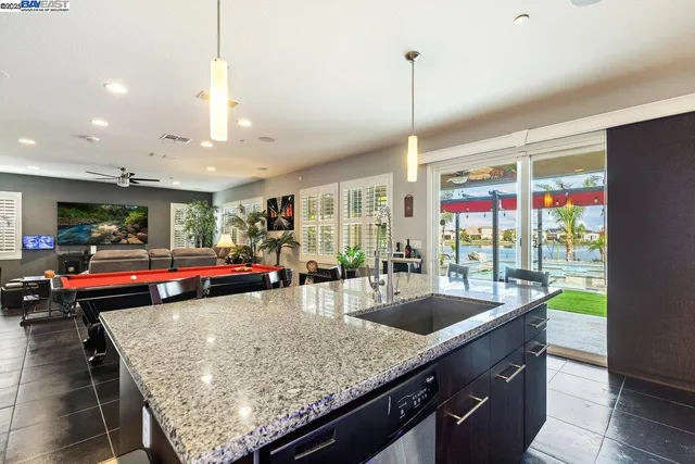 a kitchen with stainless steel appliances granite countertop a sink counter space and living room view