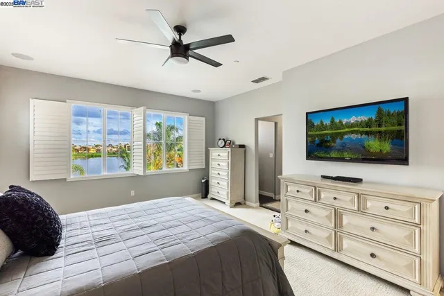 a bedroom with a bed a flat screen tv and a window