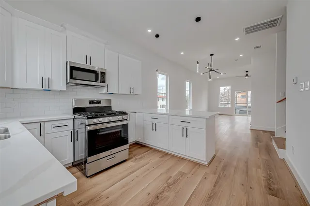 a kitchen with stainless steel appliances kitchen island granite countertop a stove a sink and white cabinets