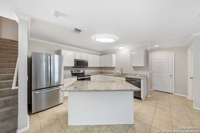a kitchen with stainless steel appliances granite countertop a refrigerator a sink a stove and a sink