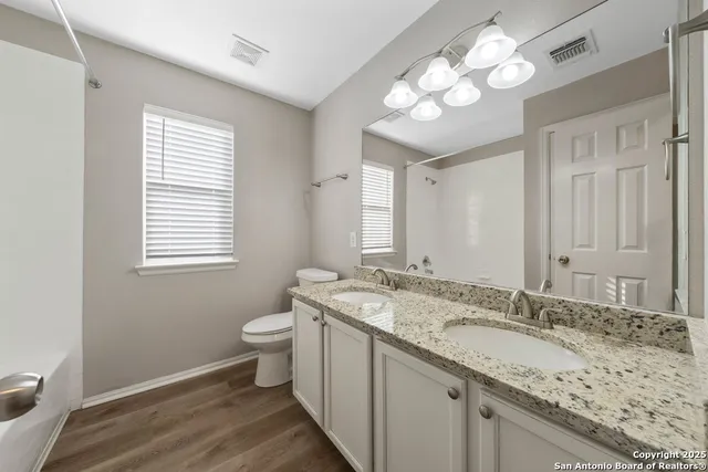 a bathroom with a granite countertop sink a toilet and a mirror