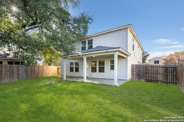 a view of a back yard with porch and wooden fence