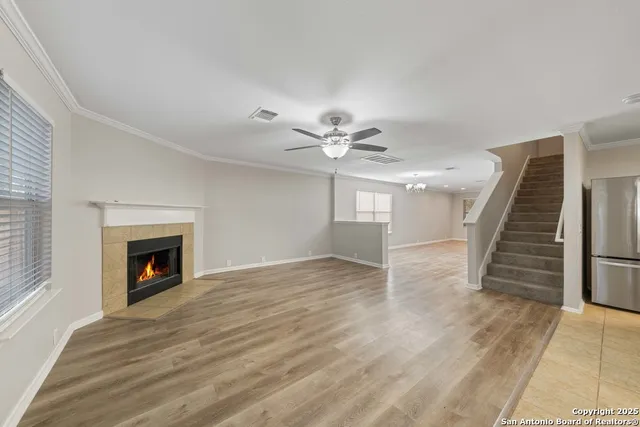 a view of an empty room with wooden floor fireplace and a window