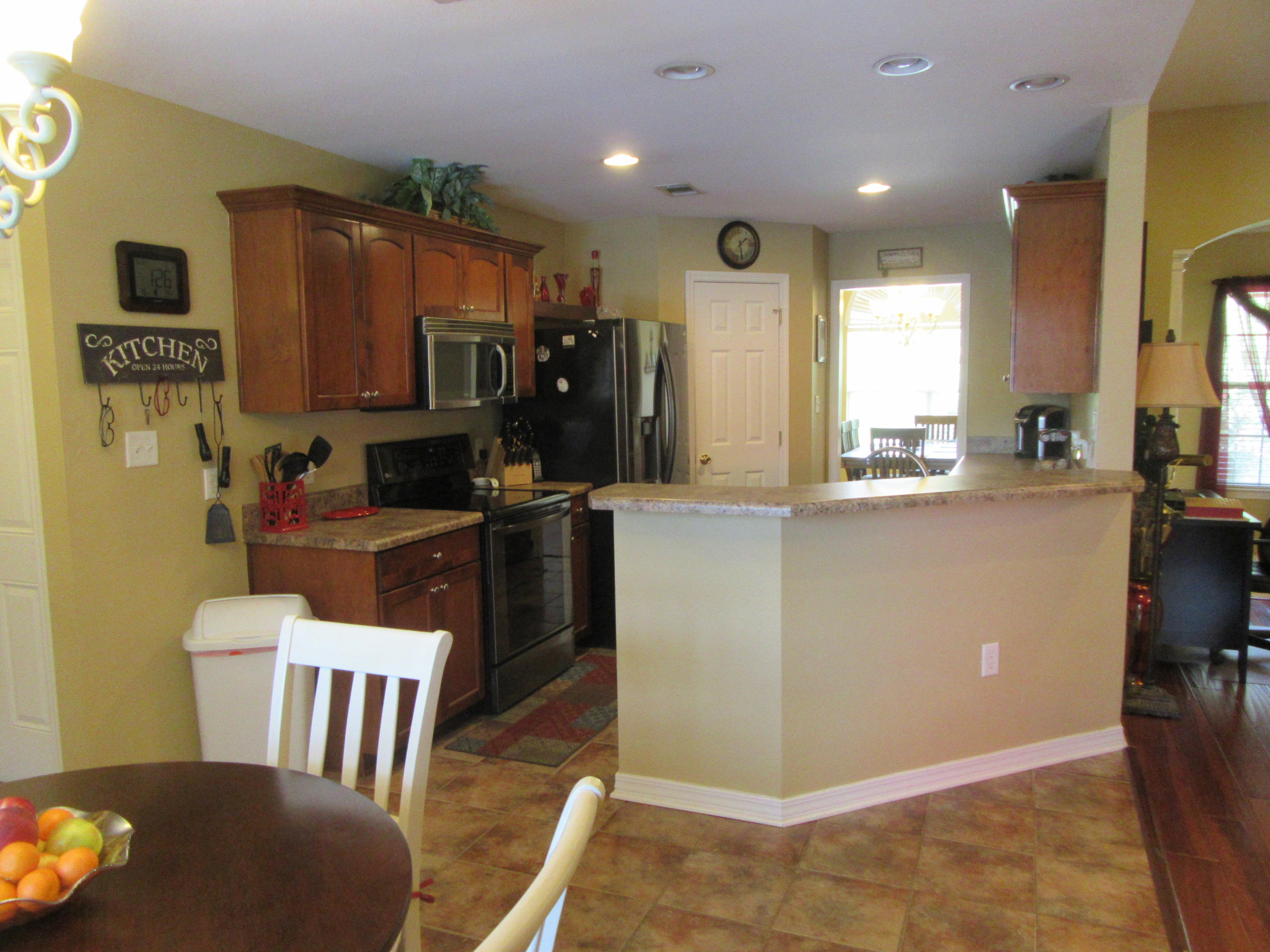 5968 Buckward Road Baker, FL 32531 - Photo 21 of 52 a kitchen with kitchen island granite countertop a refrigerator a stove top oven a sink and a dining table with garden view