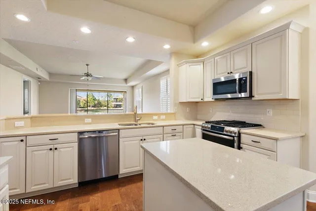 a kitchen with stainless steel appliances granite countertop a sink and a white cabinets with wooden floor
