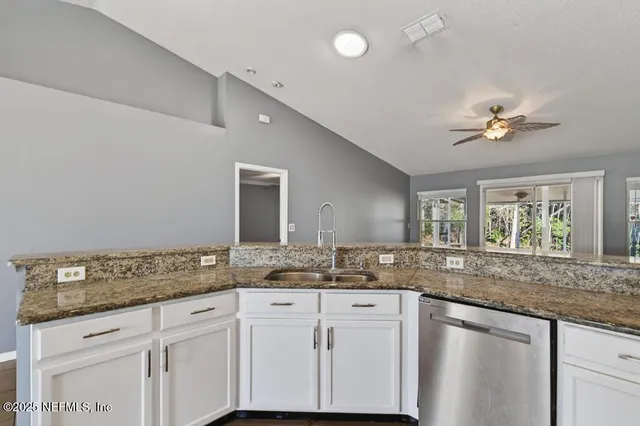 a sink with granite countertop cabinets and window