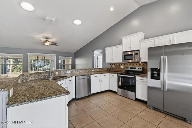 a kitchen with granite countertop a sink stainless steel appliances and cabinets