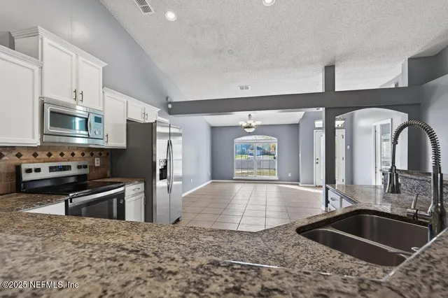 a kitchen with granite countertop a stove a sink and a microwave