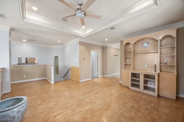 an empty room with chandelier fan and windows
