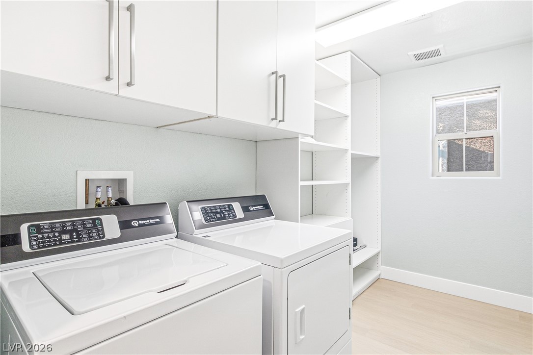 2182 Trivero Street Henderson, NV 89044 - Photo 34 of 50 Streamlined laundry area highlights modern white cabinetry, matching appliances, and warm wood-toned floors.