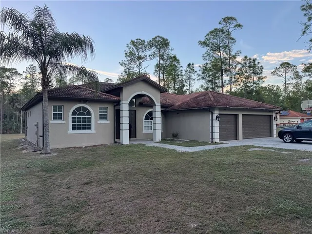 a front view of a house with a garden and trees