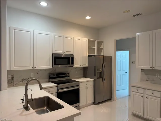 a kitchen with stainless steel appliances a refrigerator a sink a stove a microwave and wooden cabinets