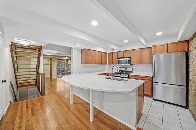 a kitchen with stainless steel appliances granite countertop a refrigerator a stove a sink dishwasher and a refrigerator with wooden floor