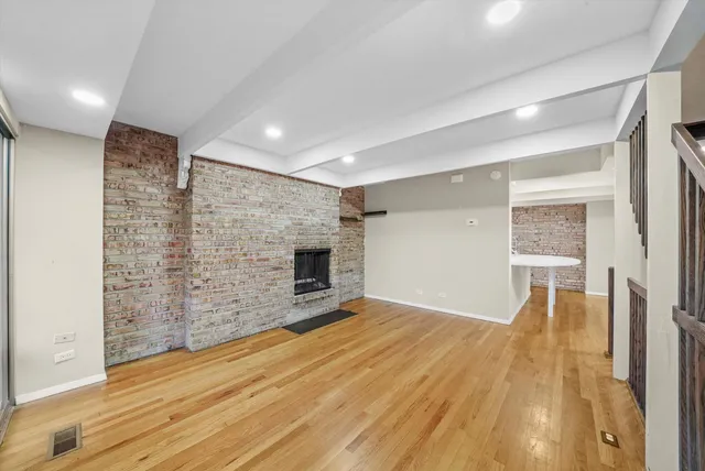 a view of empty room with wooden floor and fireplace