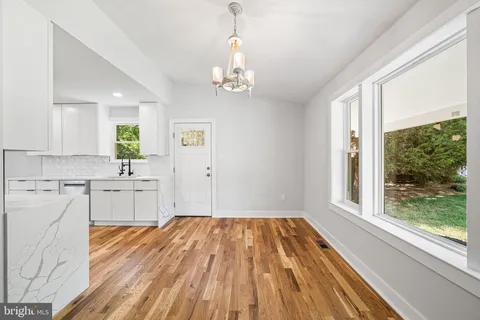 a kitchen with wooden floors sink and white cabinets