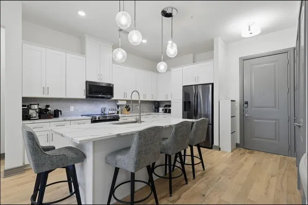 a kitchen with stainless steel appliances a table chairs refrigerator and microwave