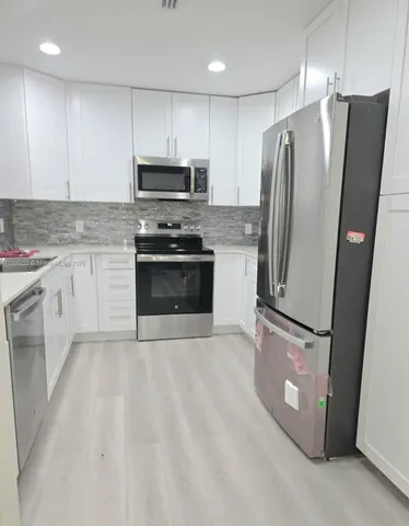 a kitchen with stainless steel appliances granite countertop a refrigerator a stove a sink and a microwave