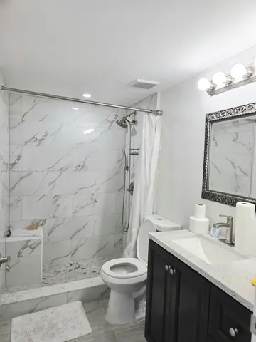 a bathroom with a granite countertop sink toilet and shower