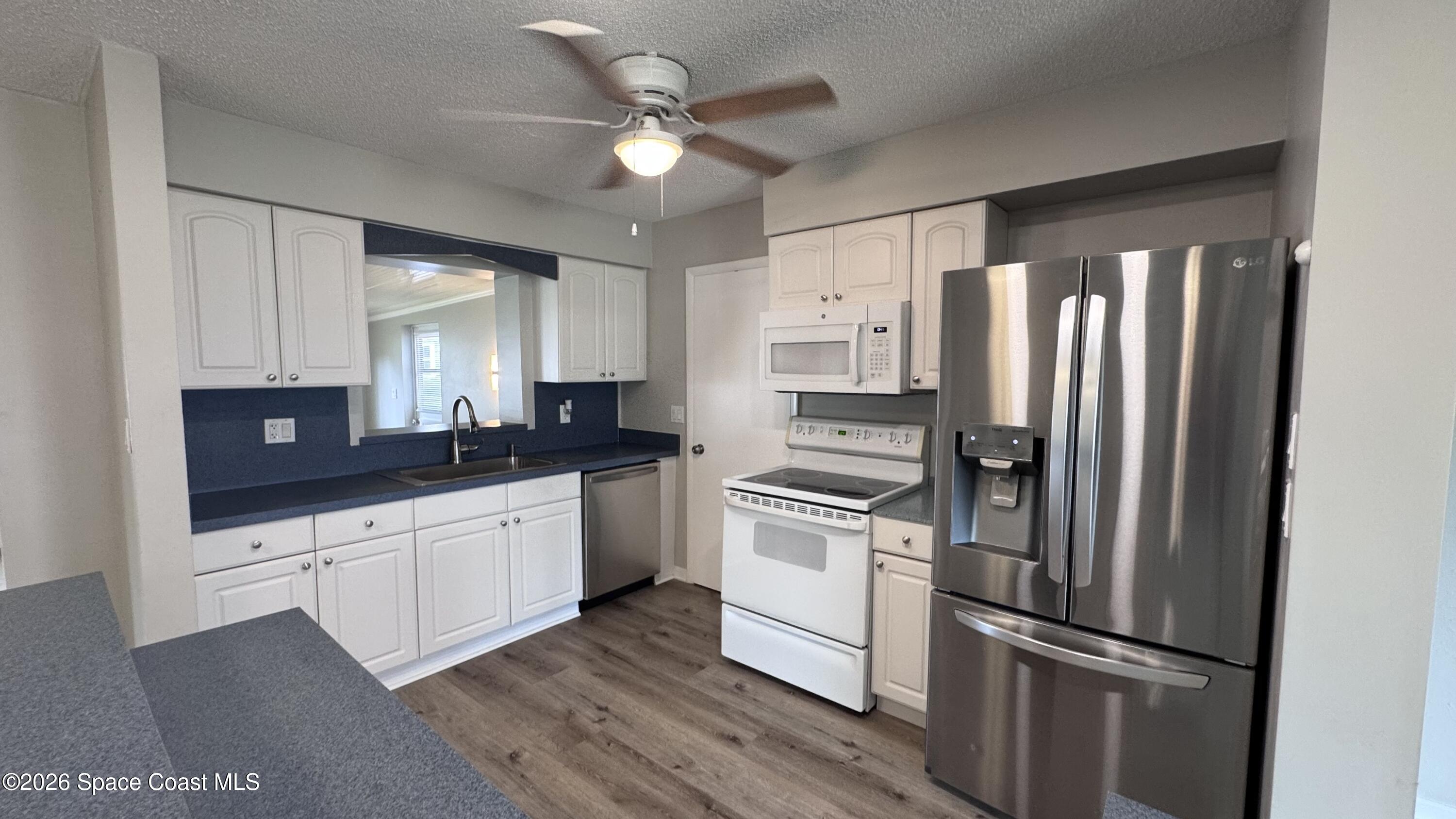 2137 Laden Road Melbourne, FL 32935 - Photo 4 of 23 a kitchen with granite countertop a refrigerator oven a sink and white cabinets