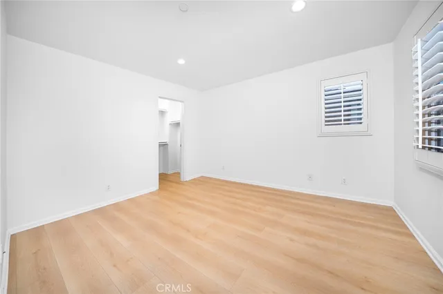 a view of a hallway with wooden floor and a bathroom
