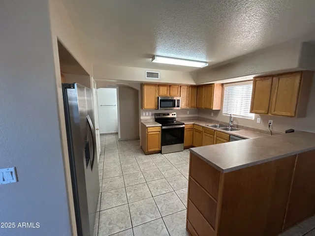 a kitchen with stainless steel appliances granite countertop a sink stove refrigerator and cabinets