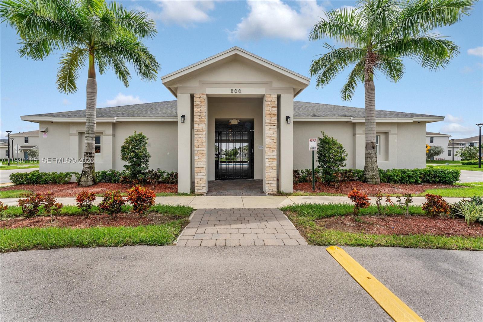 805 South E 18th Street, Unit 805 Homestead, FL 33034 - Photo 28 of 29 a front view of a house with a garden and palm trees