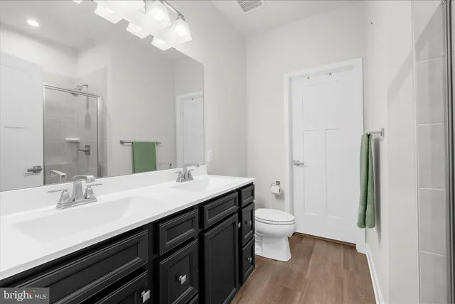 a bathroom with a sink a toilet a shower and a large mirror